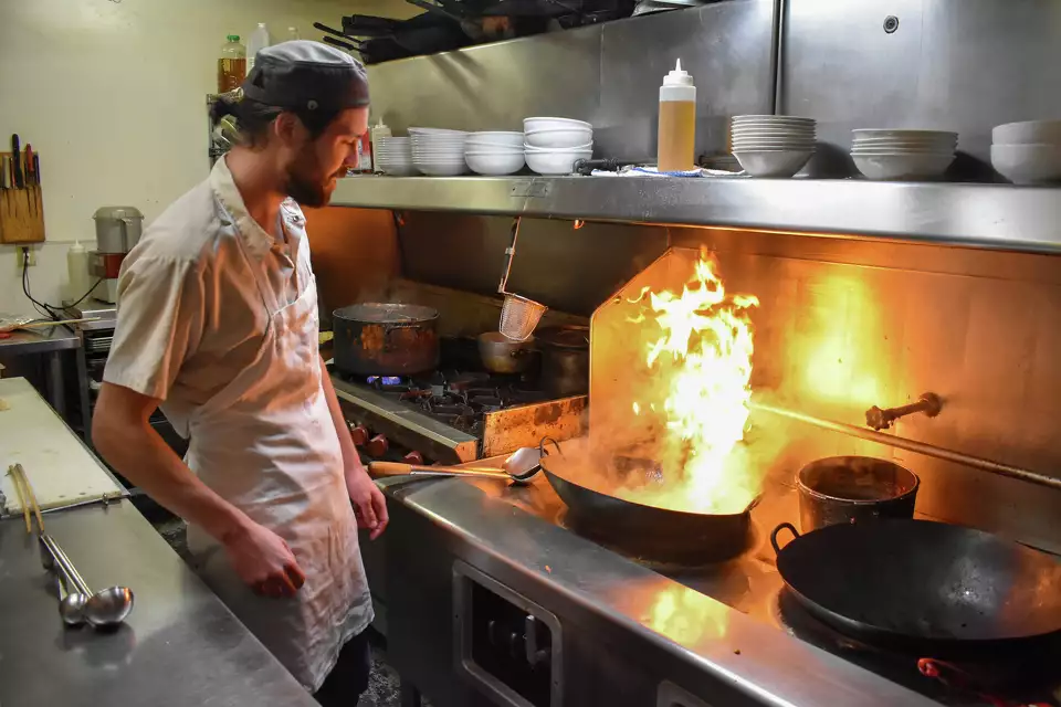 Owner Chef Russell Kwong cooking infront of a hot wok